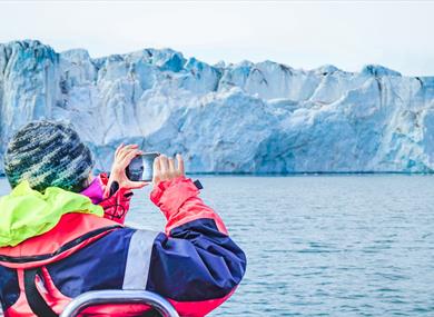 A person taking photos of a glacier