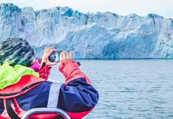 A person taking photos of a glacier