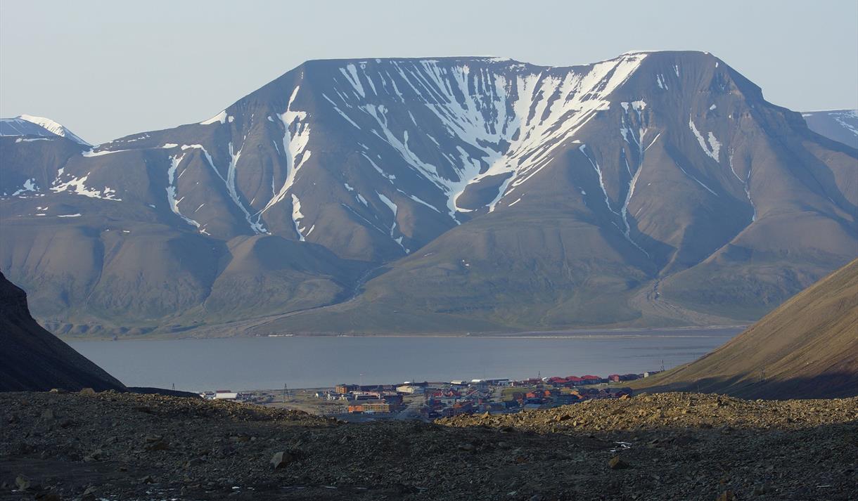 The mountain Hiorthfjellet in the background with the fjord Adventfjorden, Longyearbyen and rocky terrain in the foreground.