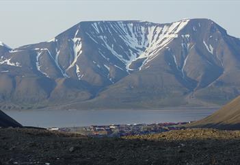 The mountain Hiorthfjellet in the background with the fjord Adventfjorden, Longyearbyen and rocky terrain in the foreground.