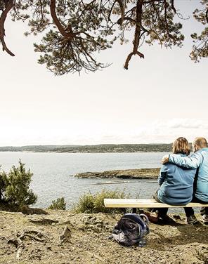par sitter på benk ved kyststien i Grenland