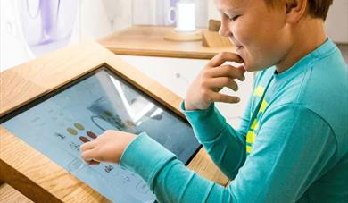 gutt ser på en interaktiv skjerm på porselensmuseet i Porsgrunn