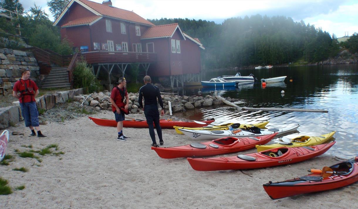 Kanoer som ligger på en strand og noen mennesker