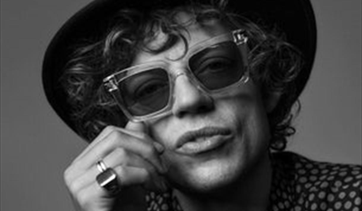 sort hvitt bilde av mann med hatt og briller