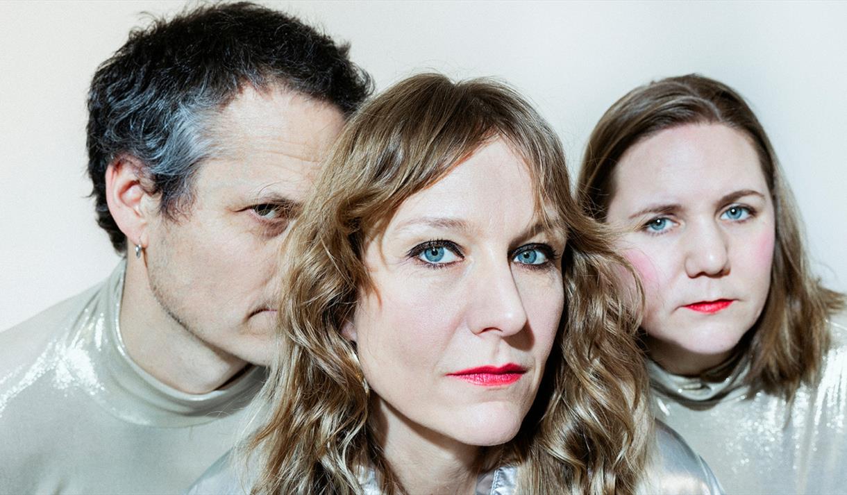 to damer og en mann, damene med rød leppestift, alle i sølv fargede klær