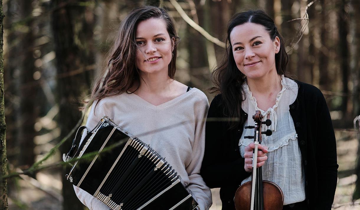 2 damer med musikkinstrumenter i skogen