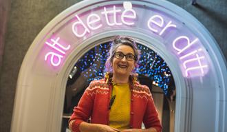 skuespiller Guandaline Sagliocco står under en portal der det står "alt dette er ditt"