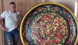 mann i hvit Tskjorte med et stort fat med rosemaling