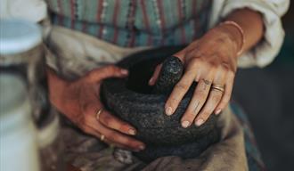 Hender rundt morter. Handverksaktivitetar på Vest-Telemark museum Eidsborg.