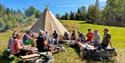 a group of men and women sit in front of a tent