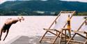 girl jumps into the water from the jetty to the Heit Telemark sauna at Lien Gård