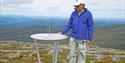 man stands next to the information board at the top of Roan