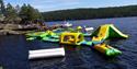 vannpark med mange oppblåsbare sklier i gult, grønt og blått, båt liggene ved brygga
