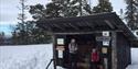 gapahuk i tre, to damer og bålpanne med snø
