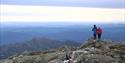 two hikers stand on top of mount Skorve and look out over the landscape