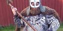 viking med maske og sverd foran en rød vegg
