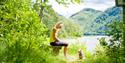 Lady sitting on a bench with a small dog in front of her