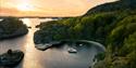 boat from Canal Boats Telemark is located in a bay at sunset