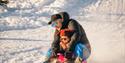 man with small child on a sled at Lifjell ski center in Bø