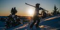 man walks up a hill with skis on his shoulder at Lifjell ski center in Bø