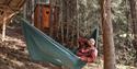 Man is lying in a hammock by a treetop iglo at Dalen