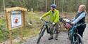 two cyclists looking at signs for the "adventure trail" at Drangedal