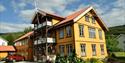 Fyresdal Bed and Breakfast on a sunny day. Flowers around the yellow house.