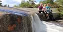 gruppe ungdom sitter ved en liten foss