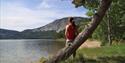 girl standing against a tree and looking out over a lake in Fyresdal