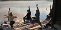 gruppe som har yoga ved vannet på Fiskebustøylen