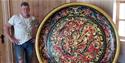 mann i hvit Tskjorte med et stort fat med rosemaling