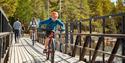 boy rides a bike over a bridge