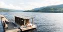 couple sits on a bench at the floating sauna Dugg Sauna in Notodden