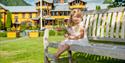 little girl sits on a bench in front of the Dalen Hotel