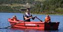 man in a rowing boat with 2 children