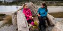 2 girls sit on a stone bench