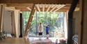 Two children standing inside a treetop cabin and looking out the window