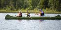 man with 2 children paddling in a canoe