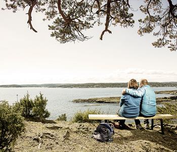 par sitter på benk ved kyststien i Grenland