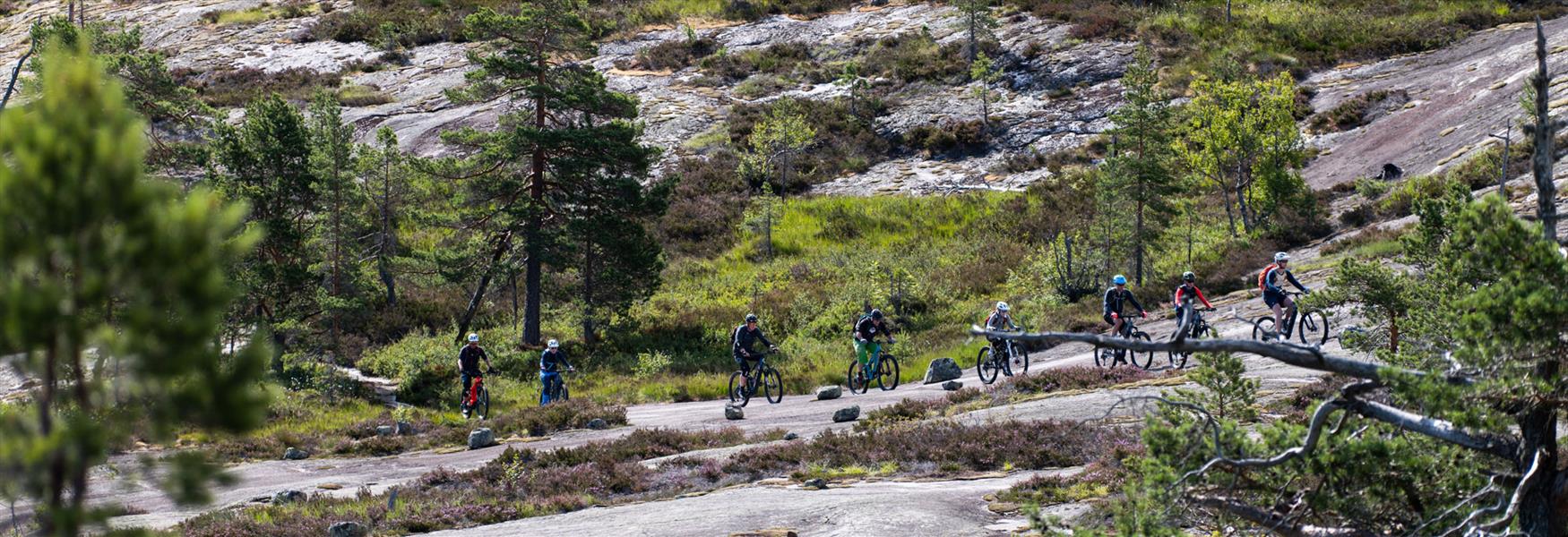 group of cyclists cycling over rocky cliffs in Nissedal
