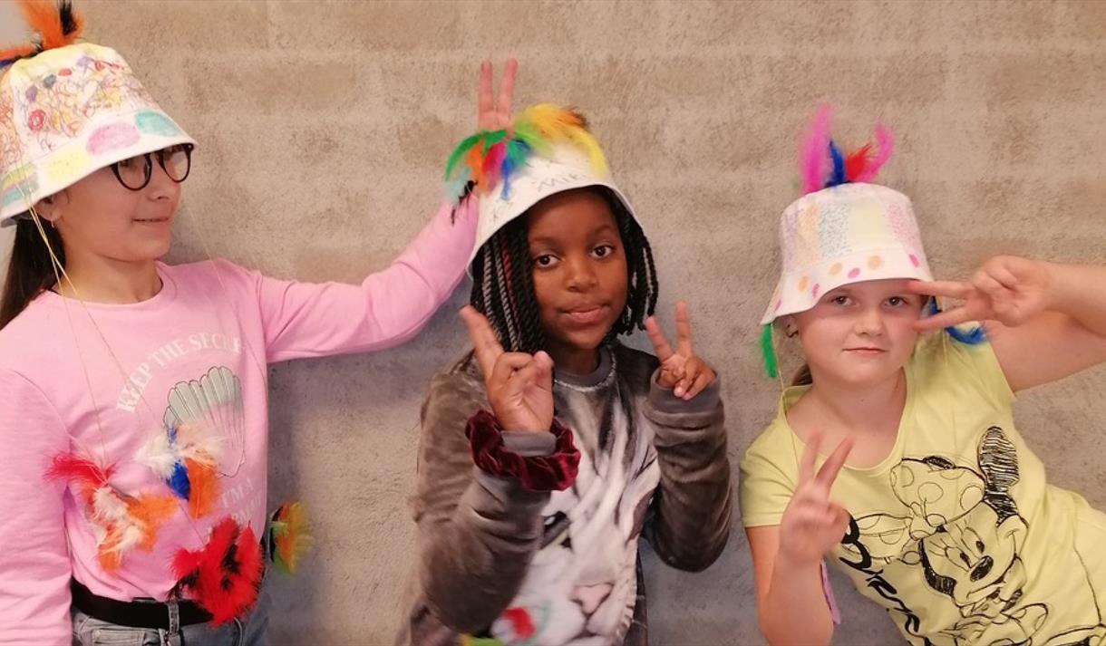 3 barn med gøyale hatter med fjær