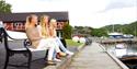 3 girls are sitting by the water's edge at Kragerø Sportell and Appartements