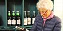 eldre dame ser på en flaske eplemost på gårdsutsalg
