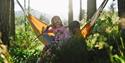 2 girls sitting in a hammock in the forest