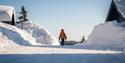 person går på en snødekt vei mellom hyttene på Lifjell Tunet i Bø