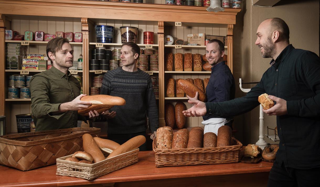4 menn på en bakeri  med brød