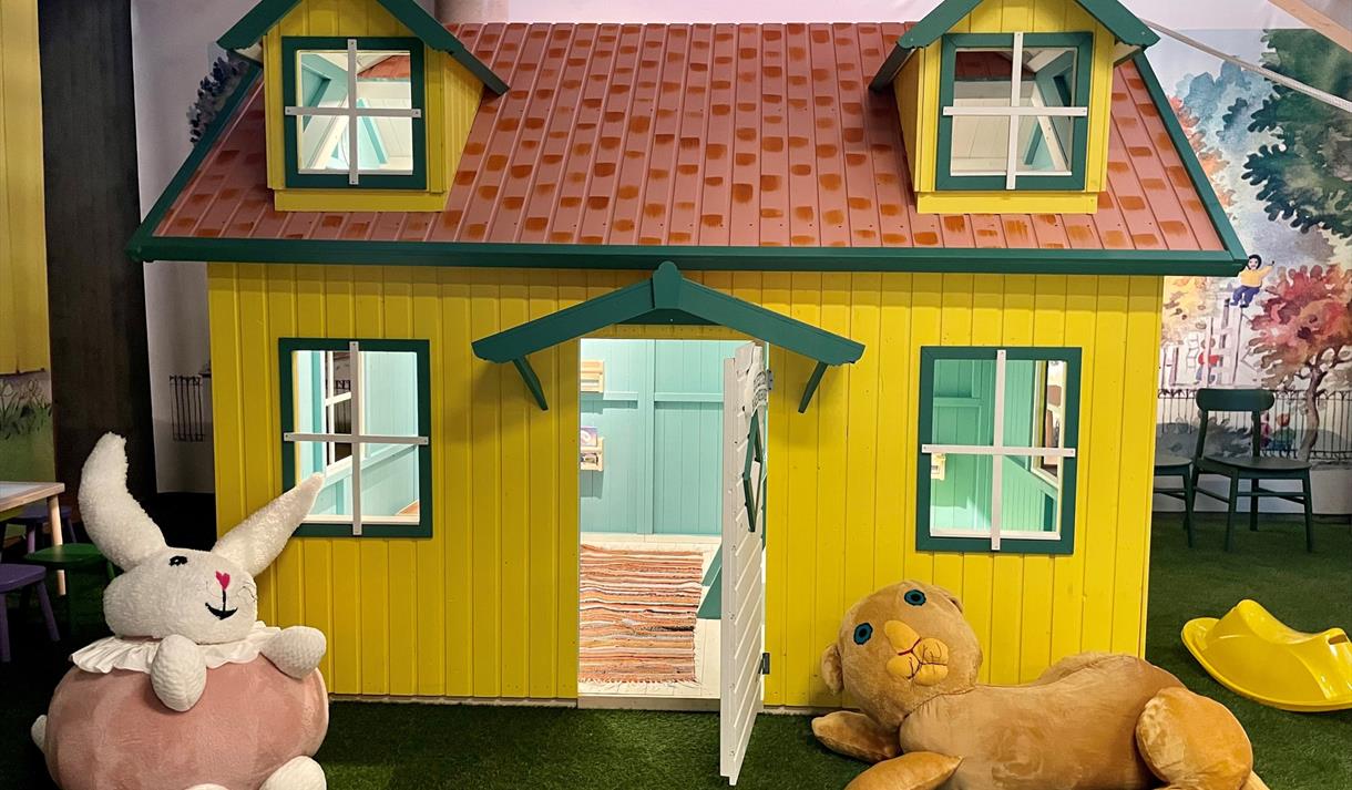 Hva skjer i Skien - Karsten og Petra utstilling. Bilde av en lekehus med tøydokkene Karsten og Petra utenfor huset