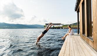 man jumps into the water from the deck of Dugg sauna in Notodden