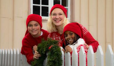 Hva skjer i Skien - Julemarked i Brekkeparken. 2 småjenter og en voksen dame med røde julegensere g røde nisseluer