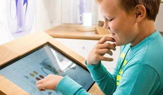 gutt ser på en interaktiv skjerm på porselensmuseet i Porsgrunn